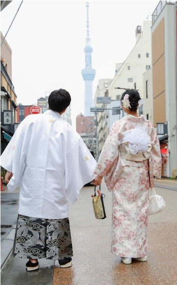 Two people in traditional attire walking on a street with a tower in the background. 4