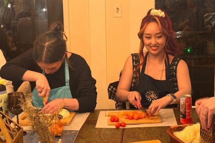 Two people preparing food at a table with vegetables and a can of soda. 3