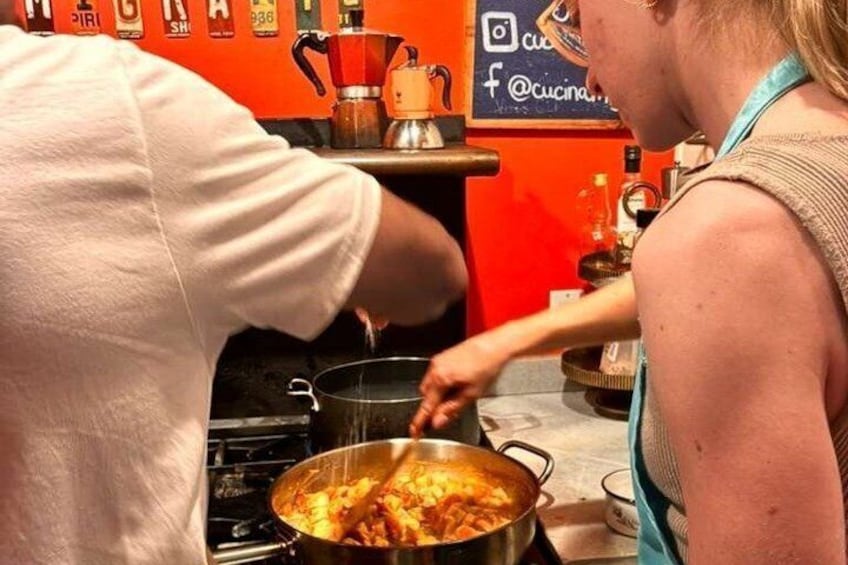 A person cooking pasta in a kitchen with a red wall and a coffee machine. 4