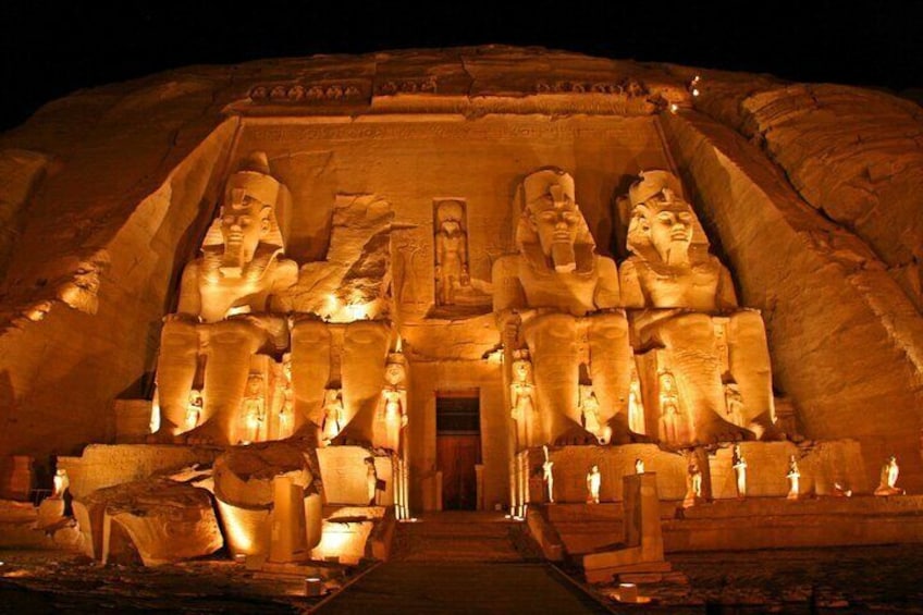 A large, illuminated pyramid structure with multiple statues of pharaohs. 1