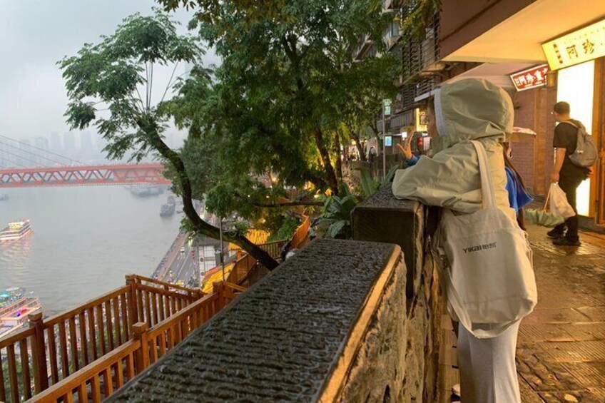 Una passeggiata lungo il fiume con una ringhiera in legno, un albero e una persona con un giubbotto bianco. 2