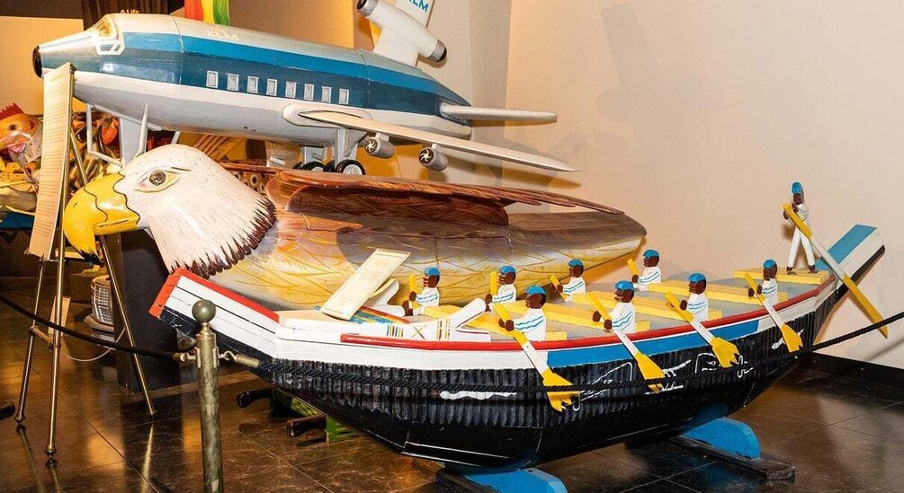 A model airplane with a figurehead, a boat with rowers, and a figure of a person on a stand. 4