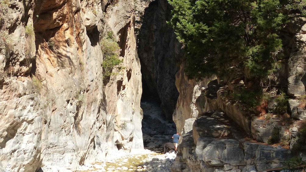 A canyon with a narrow passage, rocky terrain, and a person standing near the bottom. 2