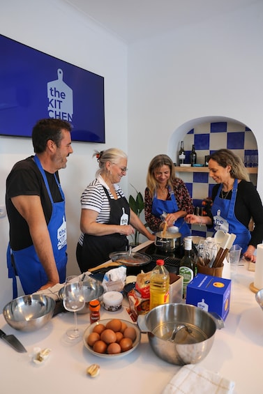 A group of people cooking in a kitchen with various ingredients and utensils on the counter. 1