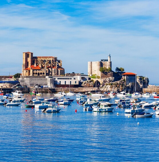 A coastal town with historic buildings, a lighthouse, and a marina with numerous boats. 1