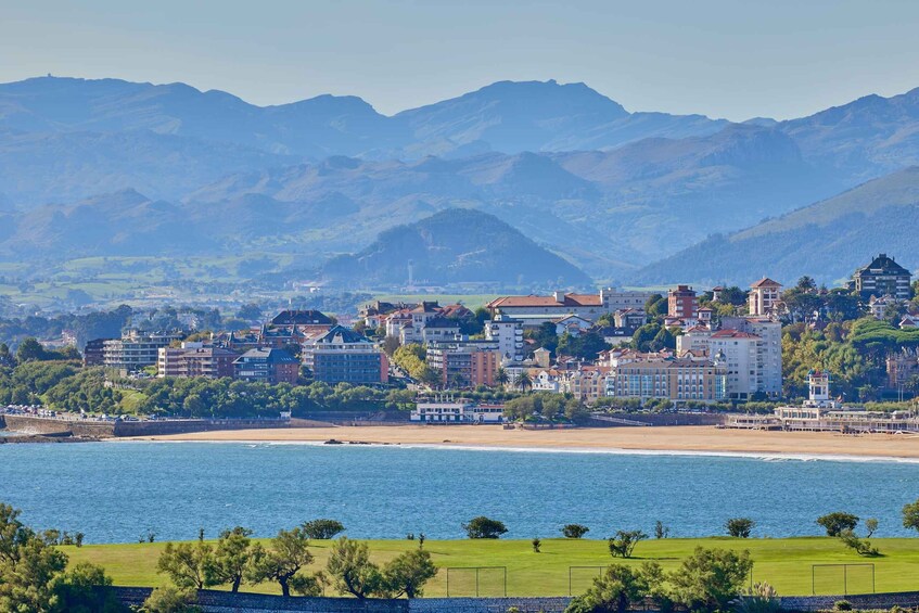 A coastal town with buildings, a beach, and mountains in the background. 4
