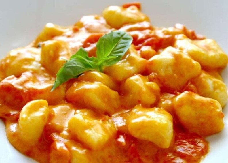 A plate of gnocchi with a tomato-based sauce and a basil leaf garnish. 5