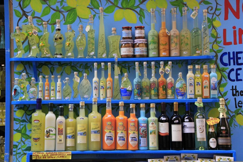 A variety of bottles on shelves with a leafy wall background. 5