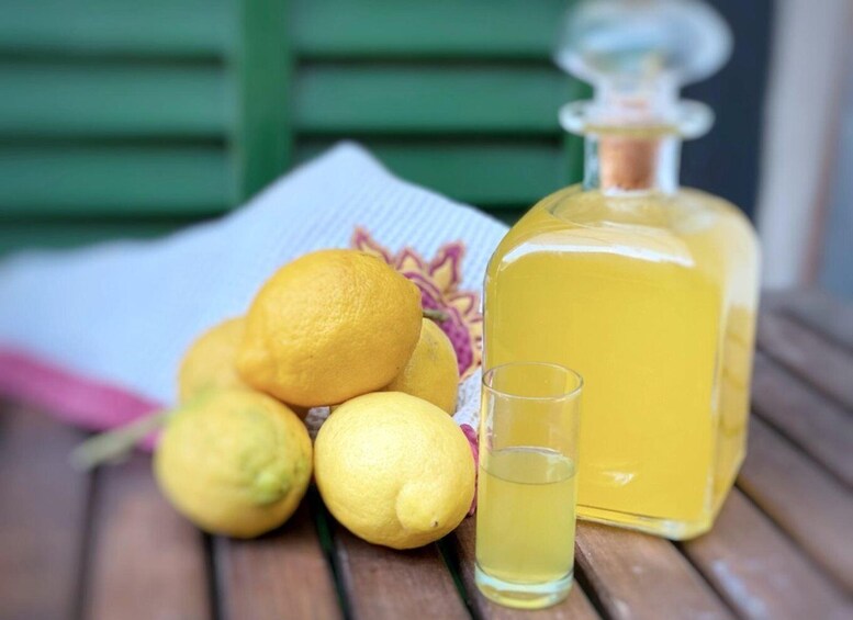 Lemons, a glass of lemon juice, and a bottle of lemon extract on a wooden surface. 1