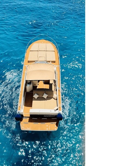 A boat with a wooden deck and a canopy, floating on clear blue water. 2