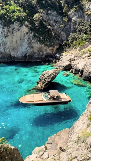 A boat anchored near a rocky coastline with clear turquoise water. 5
