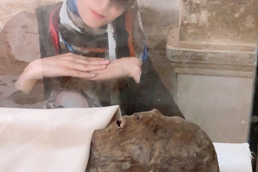 A person examining a large rock with a hole, possibly in a museum or historical site. 1