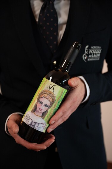 A person holding a wine bottle with a label featuring a portrait and text. 1