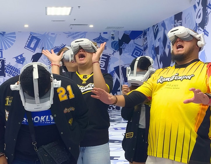People wearing VR headsets in a room with blue and white patterns on the walls. 2
