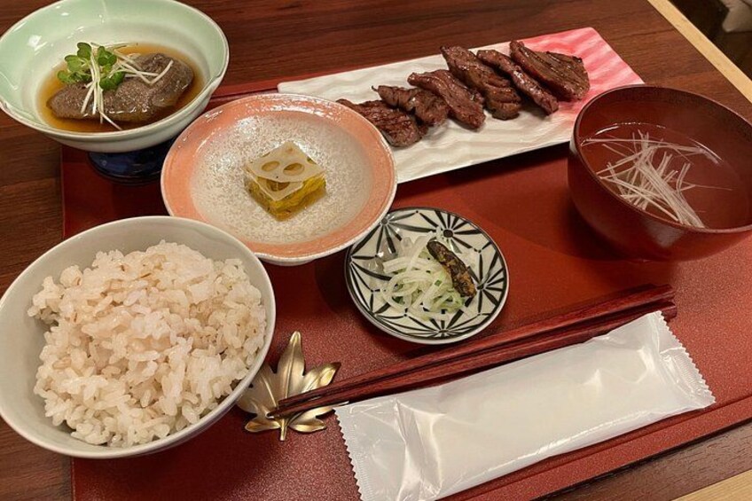 A traditional Japanese meal with rice, soup, and sliced meat on a wooden table. 5