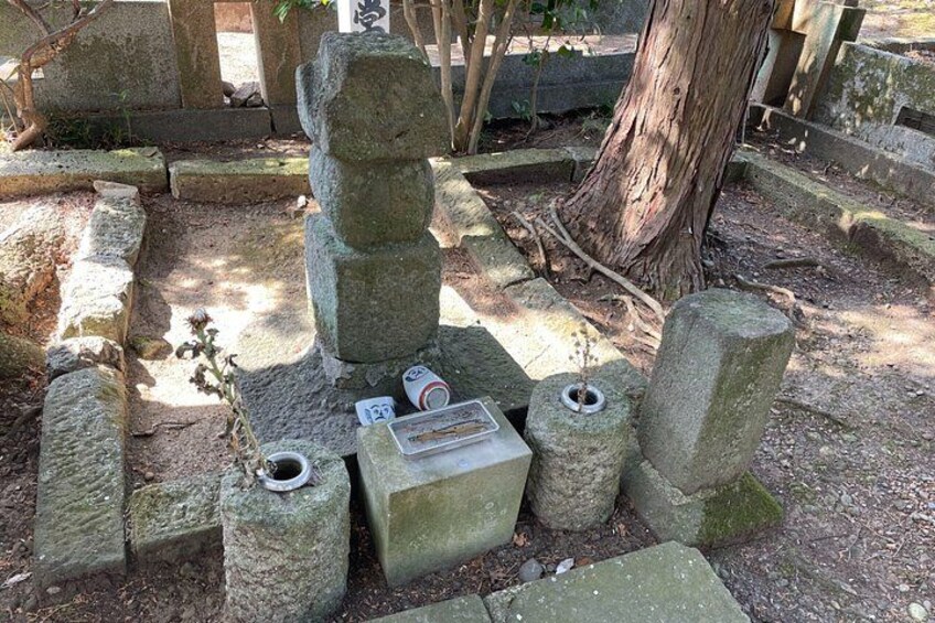A stone monument with inscriptions, surrounded by stone slabs and a tree. 5