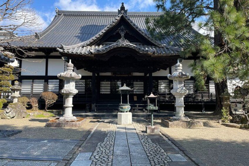 A traditional Japanese temple with a tiled roof, stone lanterns, and a stone pathway leading to the entrance. 3