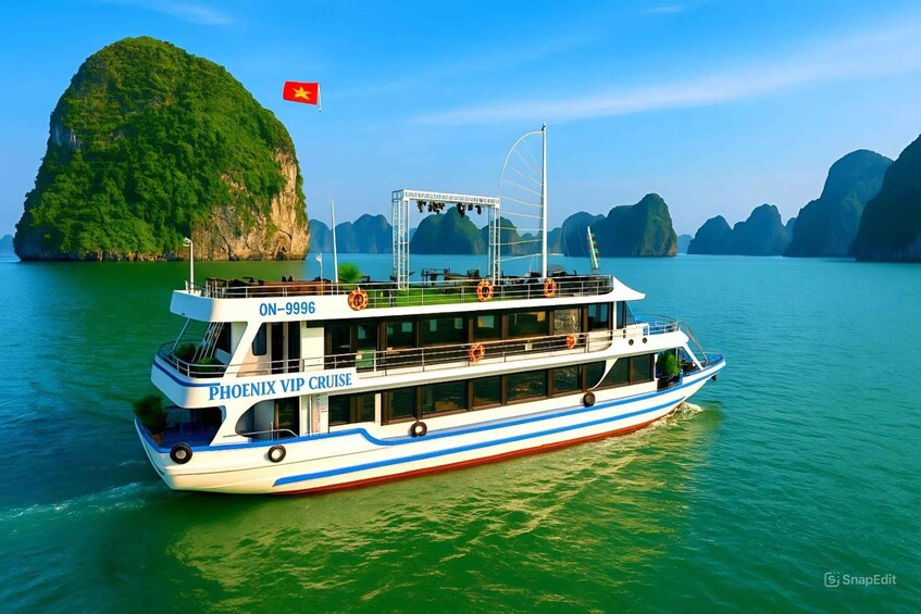 A white cruise ship with blue stripes and the name 'PHOENIX VIP CRUISE' on its side, sailing in a body of water with greenish-blue hues and a large green island in the background. 3