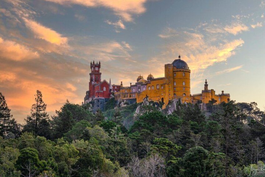 Un château avec une tour, un bâtiment à coupole et des murs rouges, situé sur une colline. 1