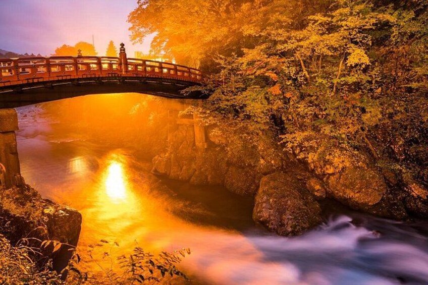 Een stenen brug over een rivier, omringd door bomen en rotsen. 2