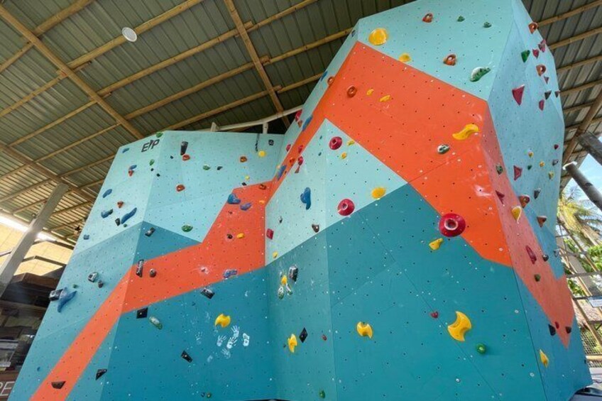 Eine große, indoor Kletterwand mit verschiedenen Griffen und einem geometrischen Muster. 1
