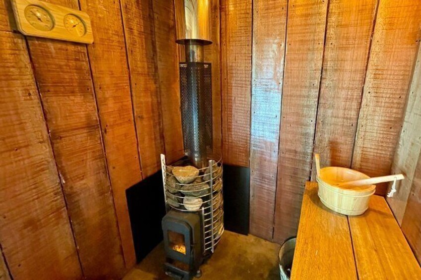 Ein Holzofen mit Metallschornstein, ein Holztisch mit einem Topf und eine Holzwand. 2