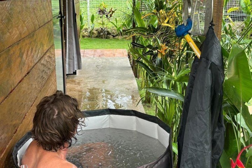 Eine Person in einer Badewanne, draußen ein Garten. 3