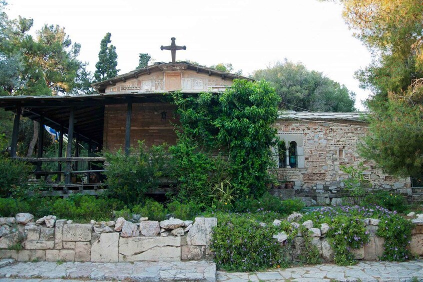 A stone church with a cross on top, surrounded by greenery and a stone wall. 2