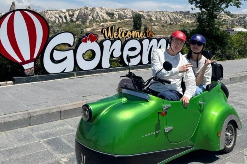 Un coche antiguo verde con sidecar estacionado frente a un cartel que dice 'Welcome to Göreme'. 5