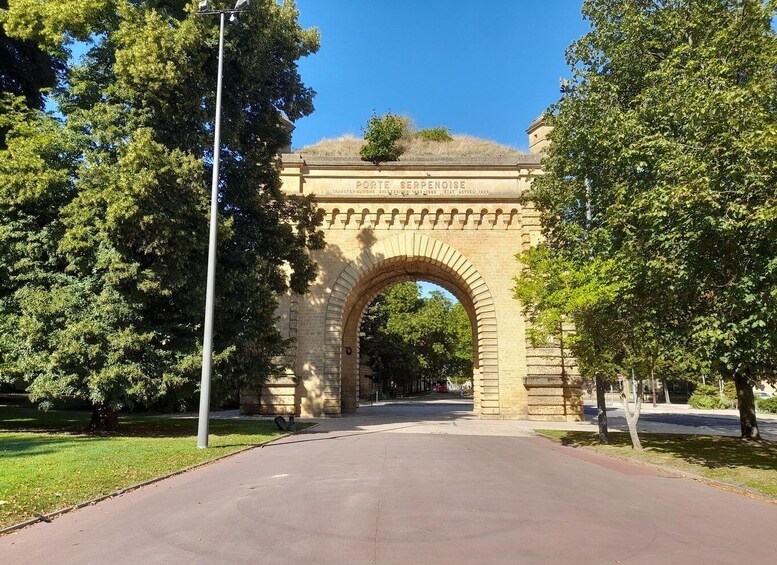 A stone archway with inscriptions, surrounded by trees and a clear sky. 5
