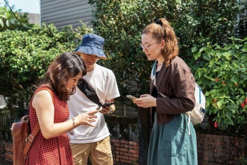 Tre persone in piedi all'aperto, una delle quali tiene in mano uno smartphone. 2