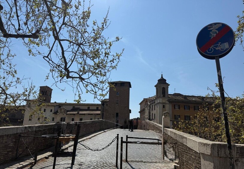 A stone bridge with a no-entry sign for bicycles, surrounded by historic buildings and a clear sky. 1