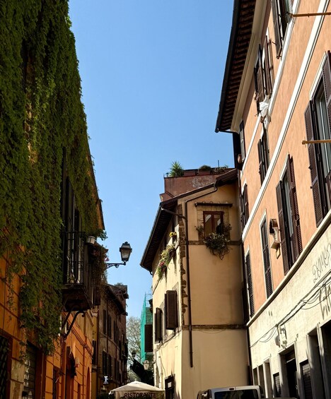 A narrow street with buildings covered in ivy, a street lamp, and a restaurant named 'Ristorante.' 3