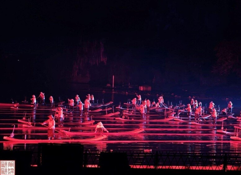 A nighttime outdoor performance with performers on boats, illuminated by red lighting. 5