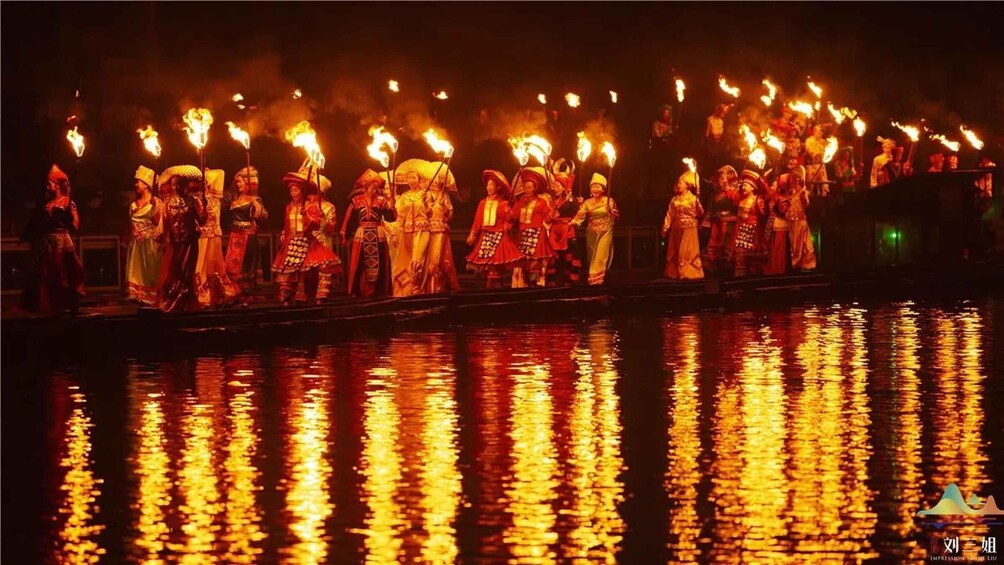 A nighttime river scene with people in traditional attire holding torches. 2
