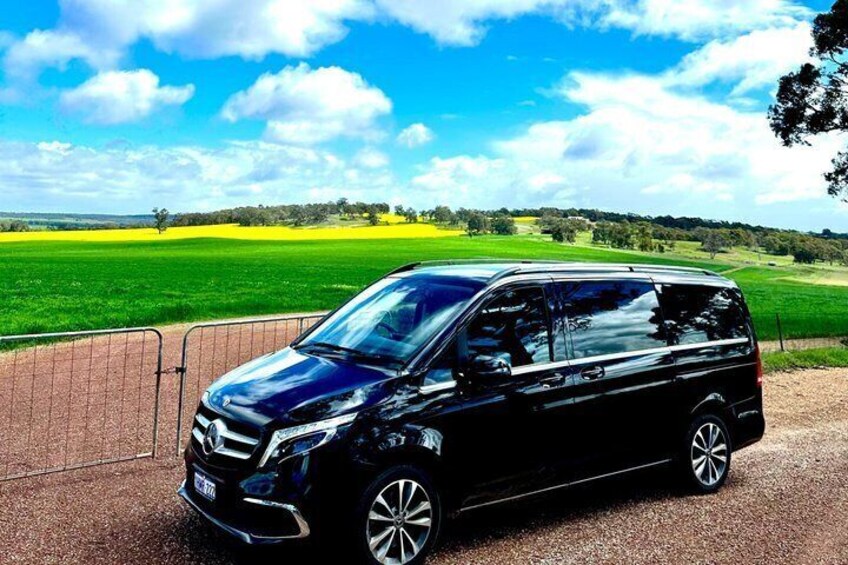 A black SUV parked on a gravel path with a rural landscape in the background. 5