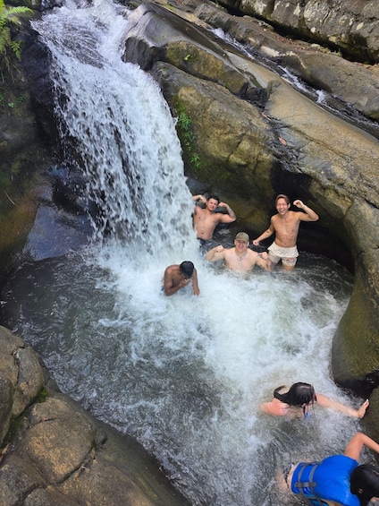 A group of people enjoying a natural water feature surrounded by rocks. 1