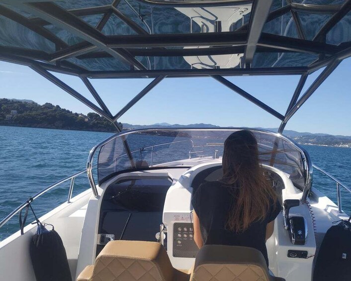 A boat with a person steering, a clear sky, and a coastline in the background. 5