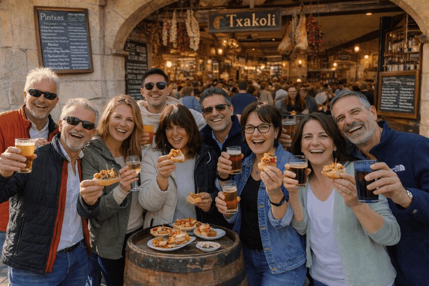 A group of people holding drinks and food at a bar with a sign reading 'Txakoli.' 5
