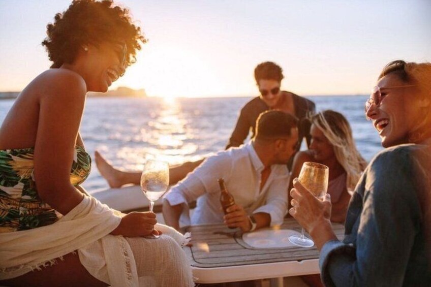 A group of people sitting at a table by the sea during sunset. 5
