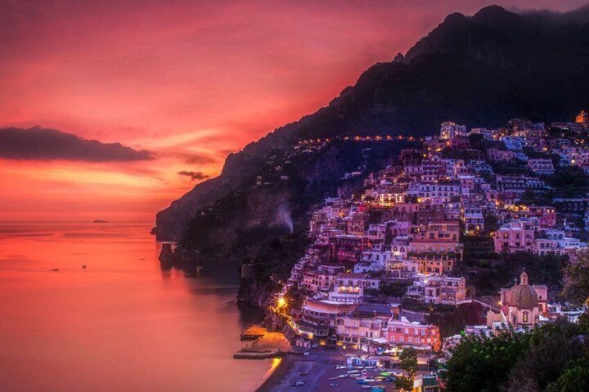 A coastal town at sunset with terraced buildings and a calm sea. 2