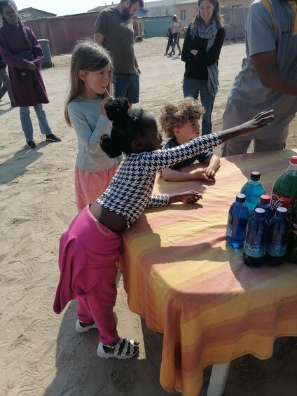 Children playing at a table with water bottles and a blanket. 4