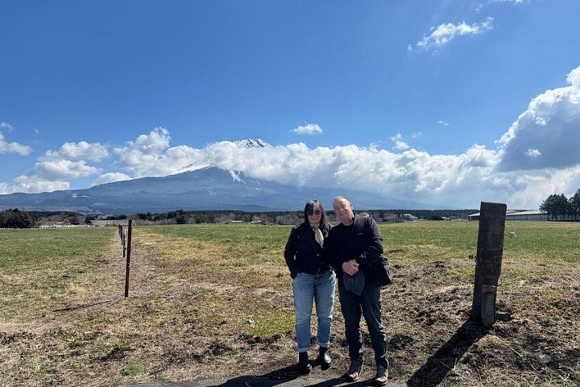Two people standing in a field with a mountain in the background. 2