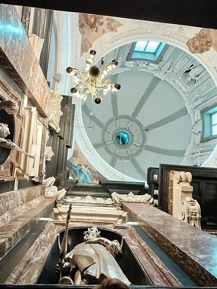 A grand interior with a large dome ceiling, marble columns, and a central chandelier. 3