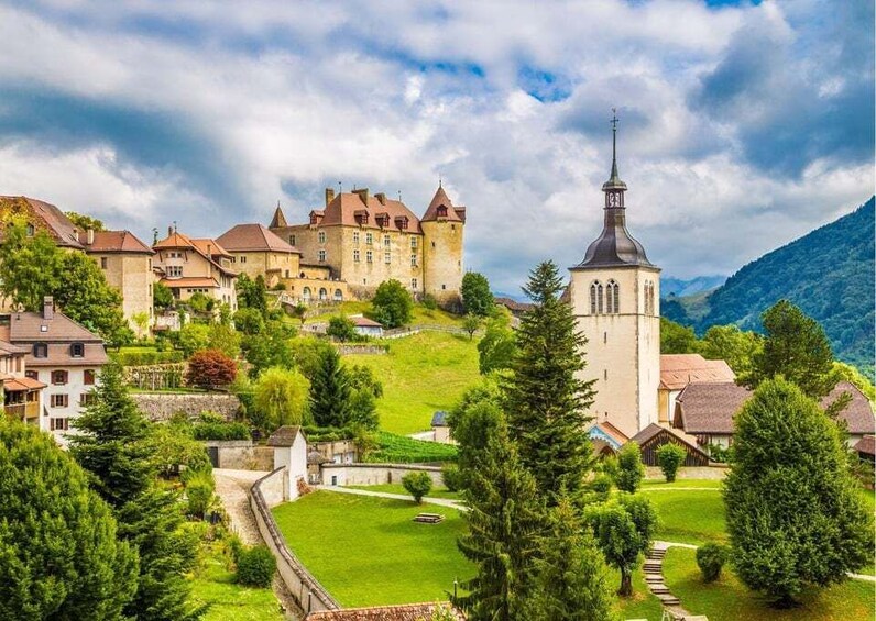 A castle with a church, surrounded by greenery and hills. 1