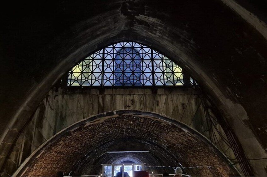 An arched stone tunnel with a patterned window at the top. 4