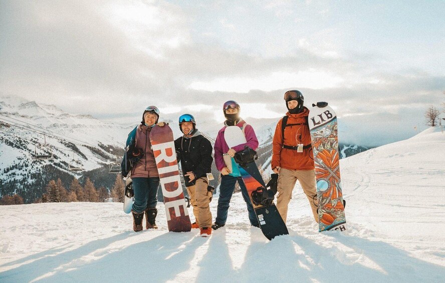 A group of people with snowboards on a snowy mountain slope. 1