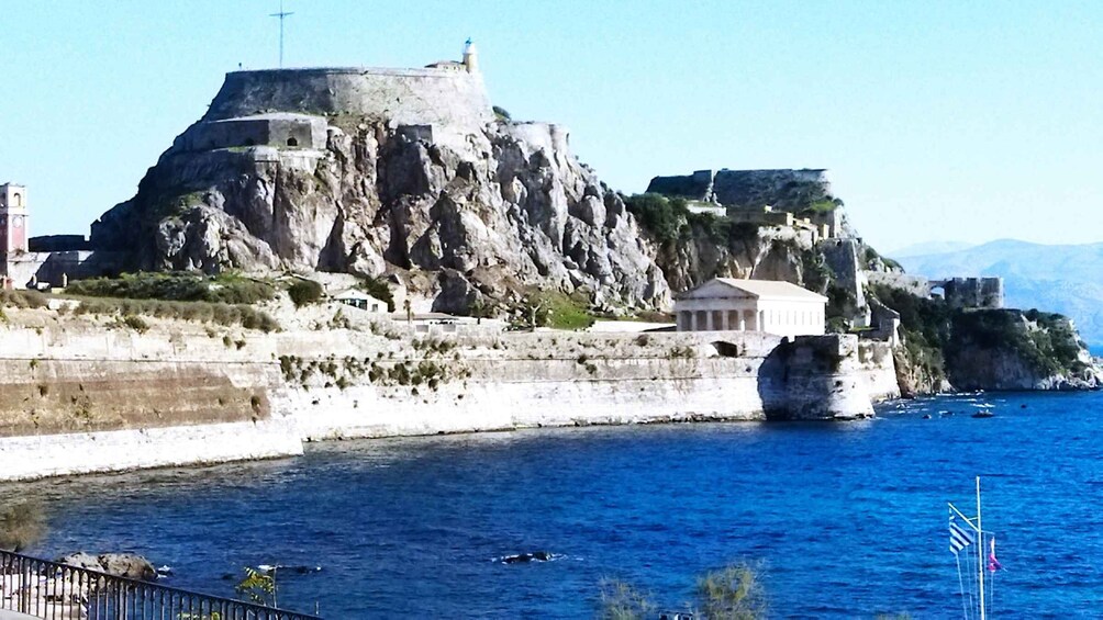 A coastal fortification with a lighthouse, a classical building, and a rocky shoreline. 2