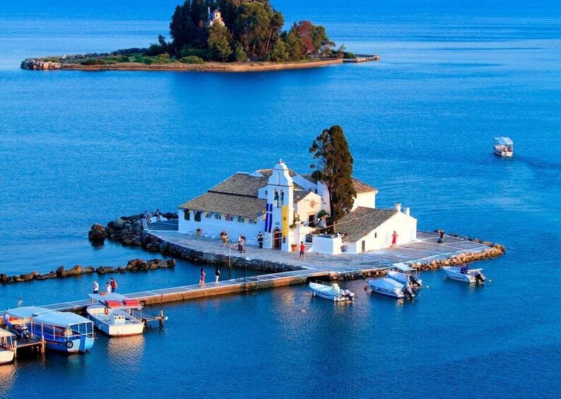 A coastal town with a white church, boats docked, and a small island in the background. 1