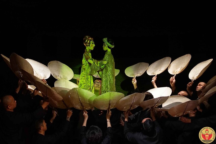 A group of people holding up large white fans in a dark setting. 4